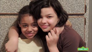Two young girls hug.