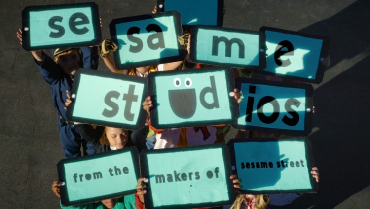 Kids hold up signs that spell out Sesame Studios.