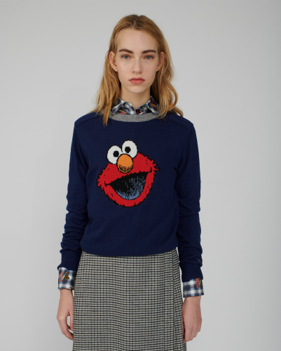 A model shows off a navy sweater embroidered with Elmos face centered on the chest.