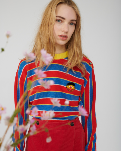 A model shows off a red and blue striped sweater embroidered with a tiny Ernie