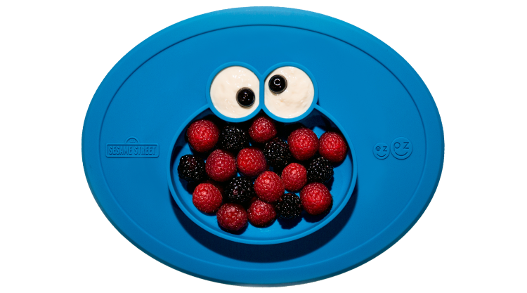 A blue, rubber child-friendly placement with food compartments shaped like Cookie Monster.