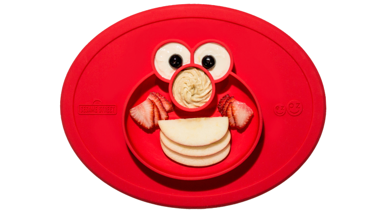 A red, rubber child-proof placement with food compartments shaped like Elmo.