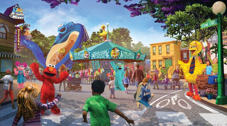 An artist's rendering inside of Sesame Place in Sand Diego. Big Bird, Abby, Elmo, and Rosita greet kids and adults as they walk into the park. A Muppet-themed carousel sits in the center of the town square entrance.