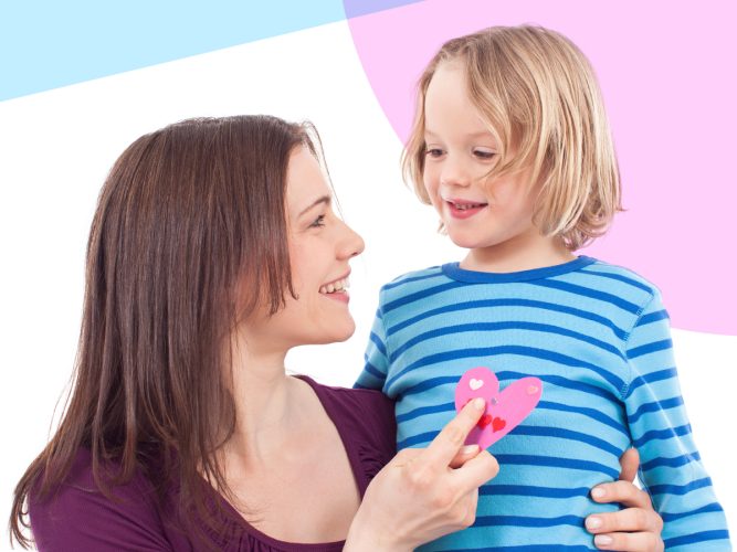 A parent holds a child with their arts and crafts project