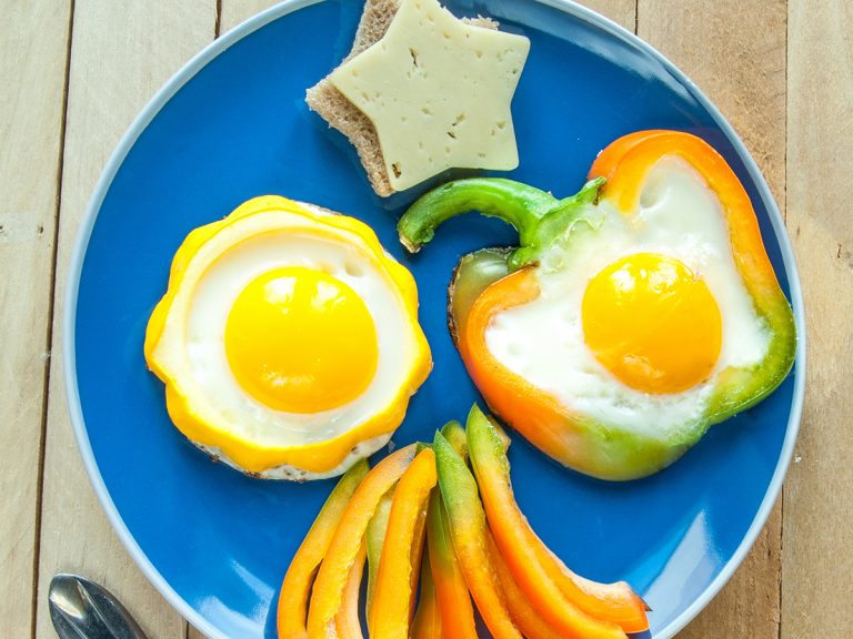 A blue plate with vegetables and sunny side up eggs