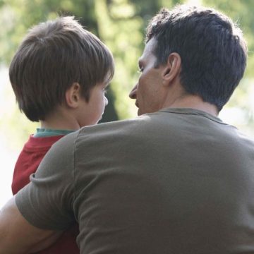 A little boy being held by his father.