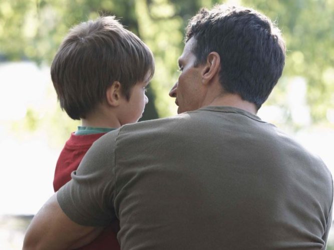 A little boy being held by his father.