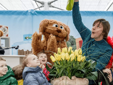 Sesame Street Muppets and a crowd of children watering tulips.