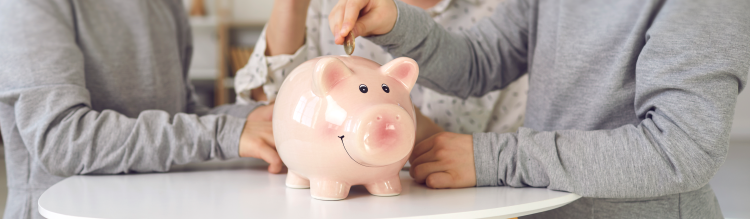 A child adds money into a classic pink piggy bank.