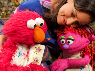 Nina gives Elmo and Lily a big hug.