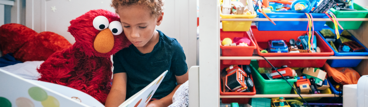 Elmo and a young boy read a book together.