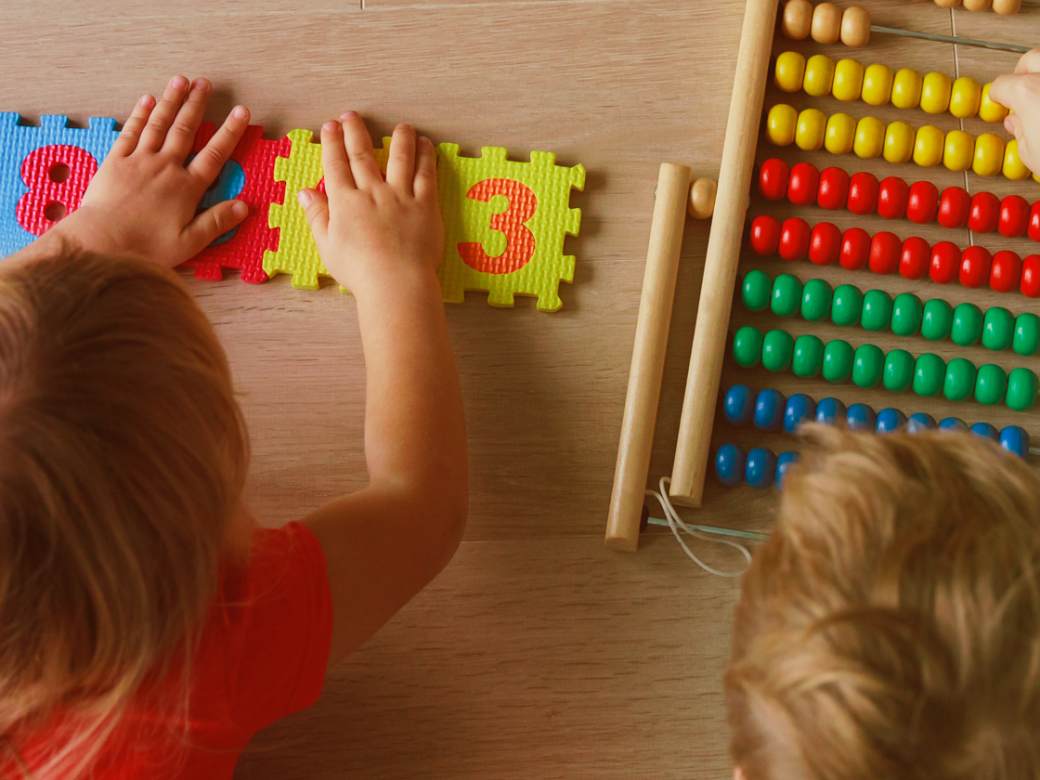 Two young children play with number blocks and an abacus.