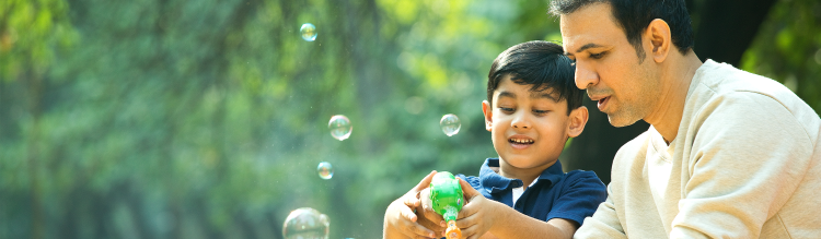 A father helps his son blow bubbles