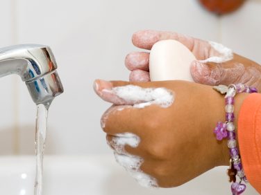 A child staying healthy by washing their hands with soap and water.