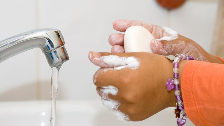 A child staying healthy by washing their hands with soap and water.