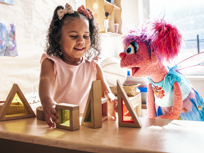 A child and Abby play with blocks.