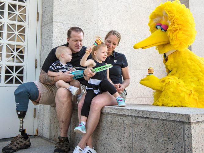 A military family plays instruments with Big Bird.