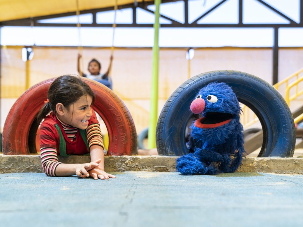 Grover on a playground with a kid.