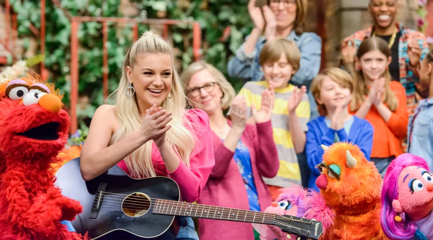 Children, adults, and Muppets clapping with Kelsea Ballerini