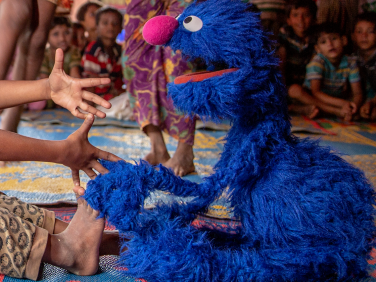 Grover and child about too hug.