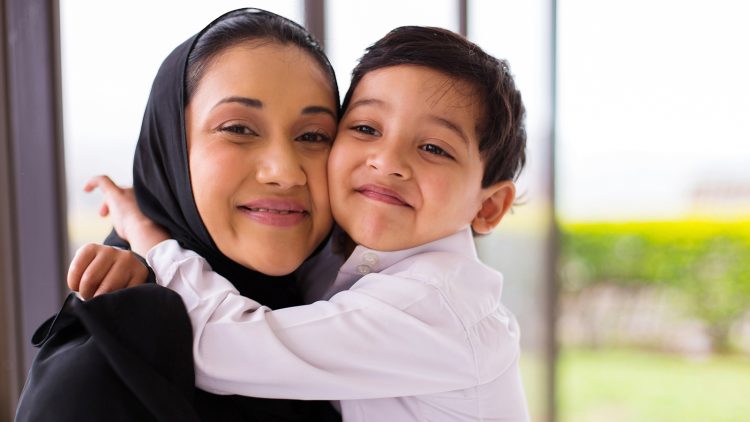 Mother and Son hug each other and smile into camera.