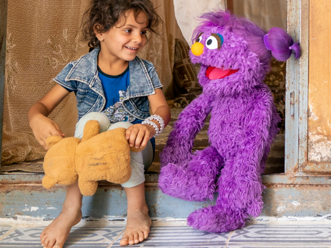 Sesame Workshop Muppet and child with teddy bear.