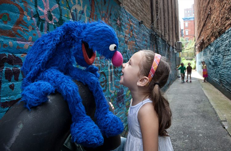 Grover and a young child touch noses.