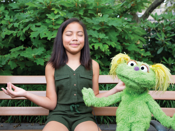 A child and Karli strike a meditative pose together.