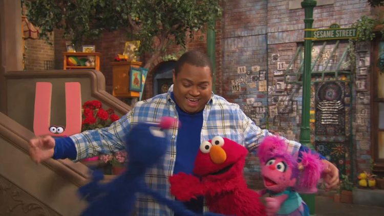 Grover, Elmo, and Abby give Chris Robinson a group hug.
