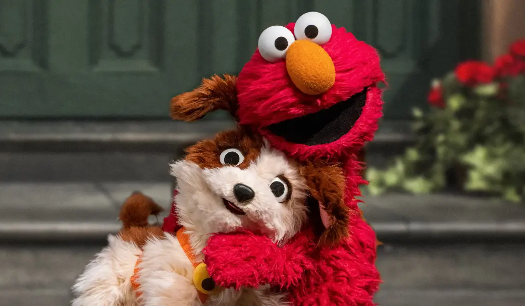 Elmo hugs a small dog.