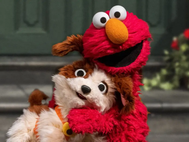 Elmo hugs a small dog.