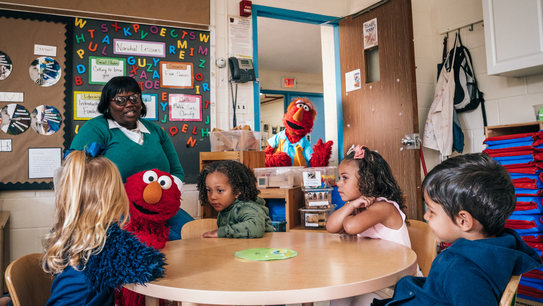 Elmo and his dad Louie in a classroom with young students.