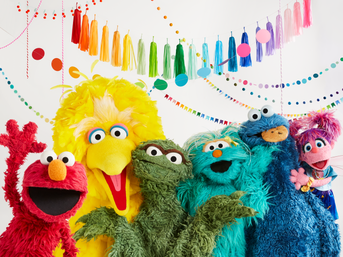 Elmo, Ernie, Bert, Big Bird, Oscar the Grouch, Rosita, Cookie Monster, Grover, and Rosita all pose together.