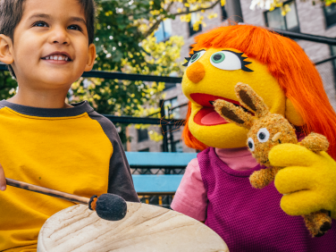 Julia in the park with a child playing the drum