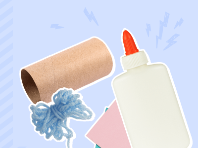 A bottle of craft glue lays next to a toilet paper cardboard roll and a bundle of blue yarn.