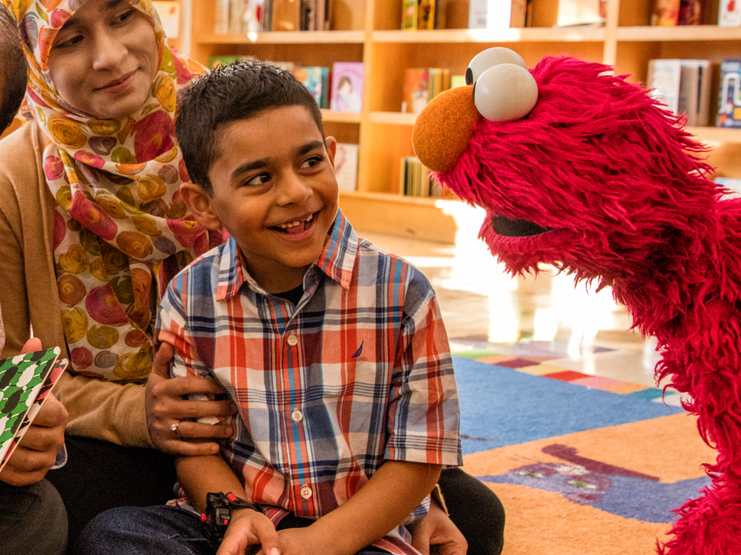 A family reading with Elmo at a library
