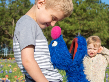 Grover plays with a family in a meadow