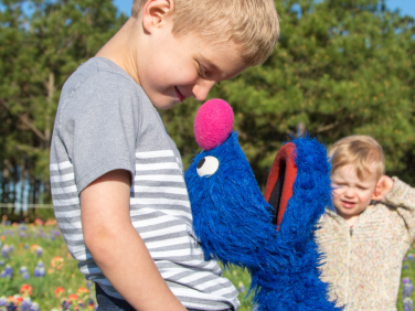 Grover plays with a family in a meadow.