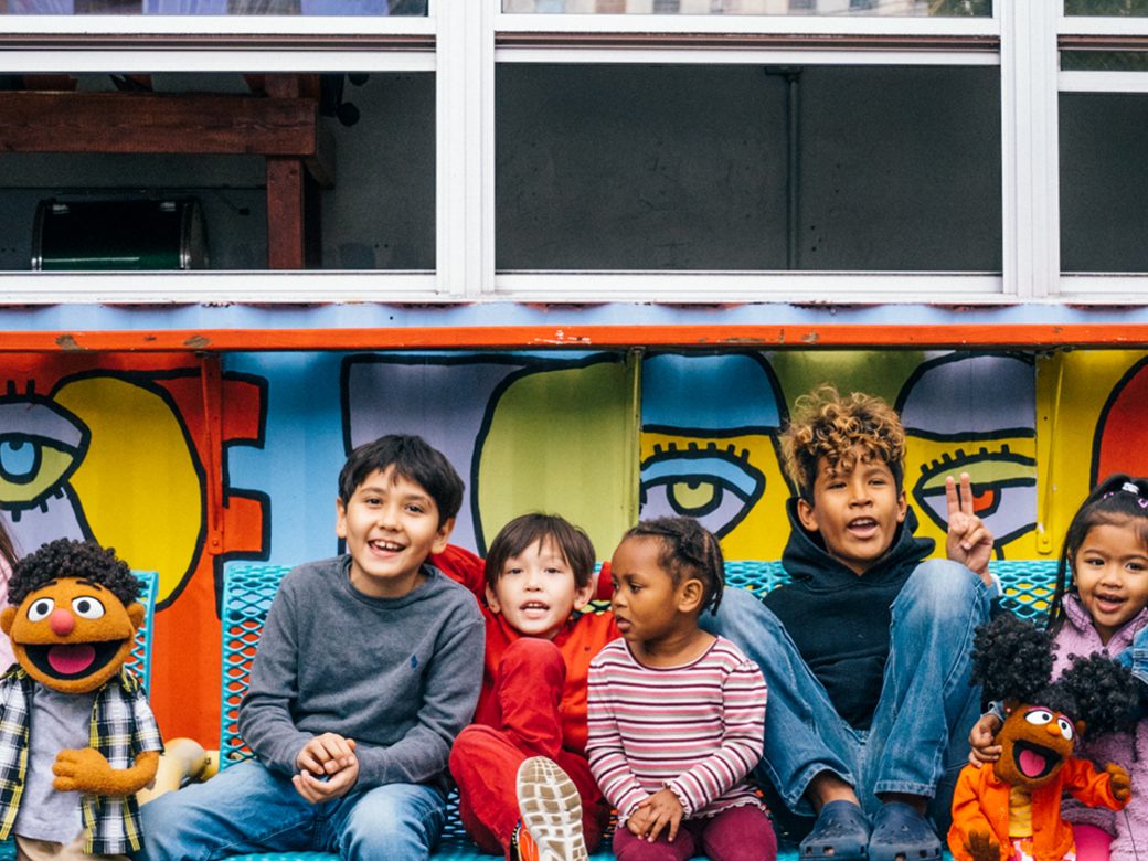 Sesame Street Muppets and kids on a bench.