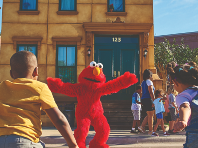 Elmo and Abby greet adults and children at a theme park.