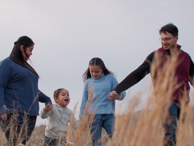 A family walks through a field holding hands