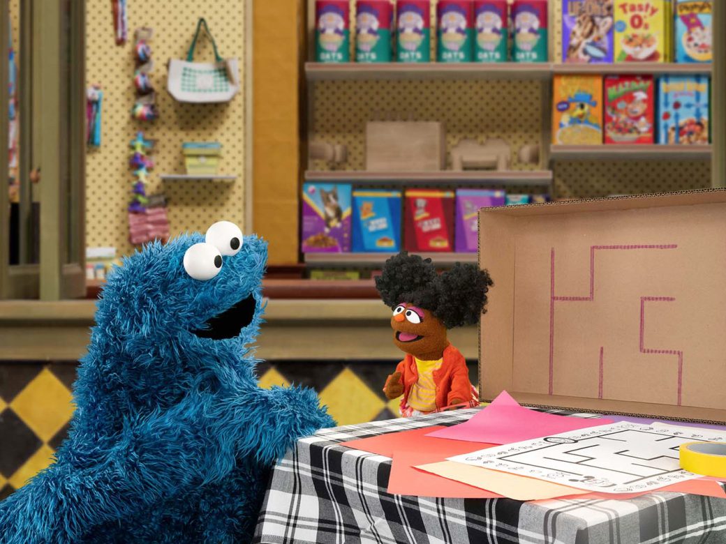 Cookie Monster sits at a table with Gabrielle