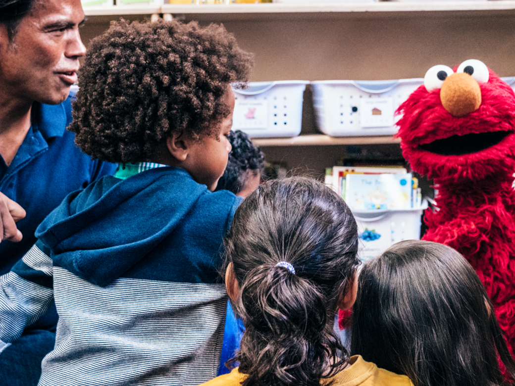 Elmo with a provider and a group of children.
