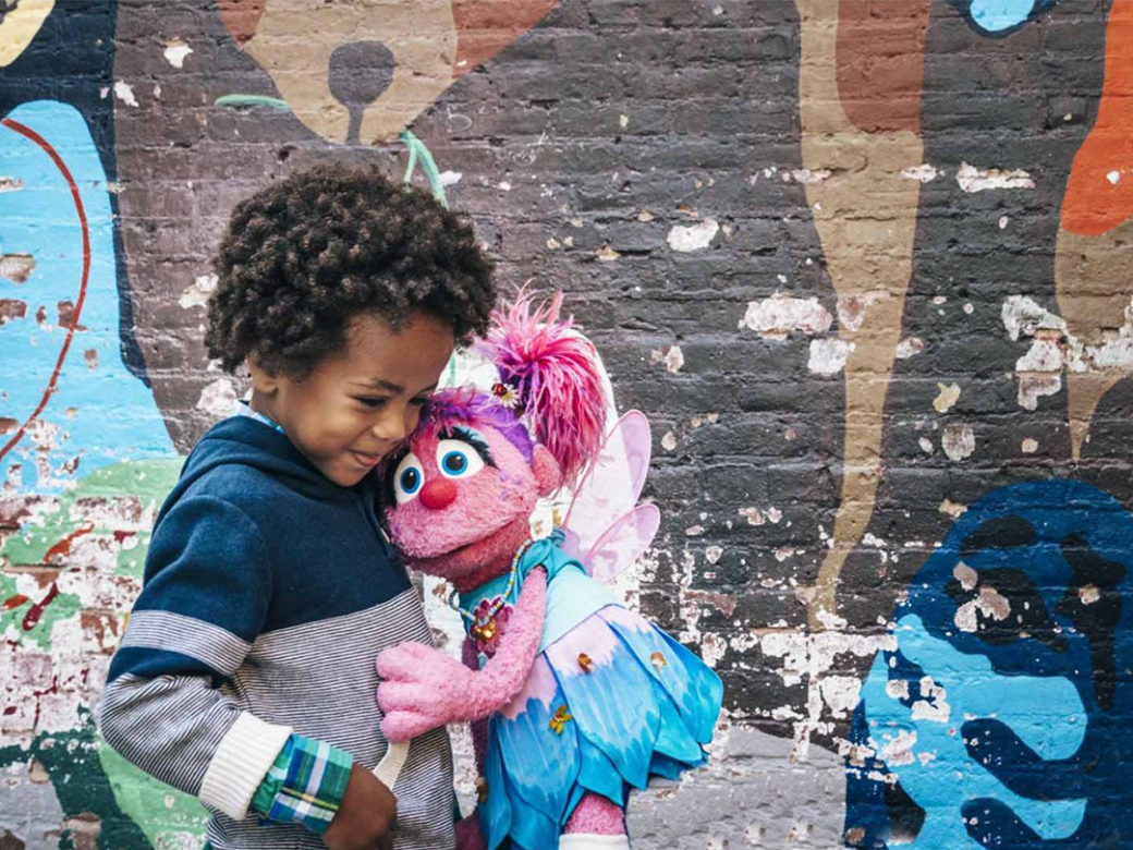 Abby hugging a small child against a mural.