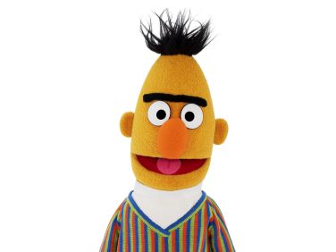 Bert smiles at us. He wears a vertically pinstriped sweater.