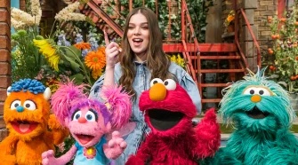 Hailee Steinfeld poses behind muppets.