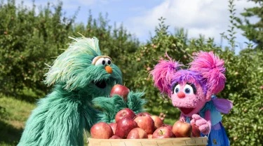 Rosita and Abby Cadabby in an apple orchard with a barrel of apples