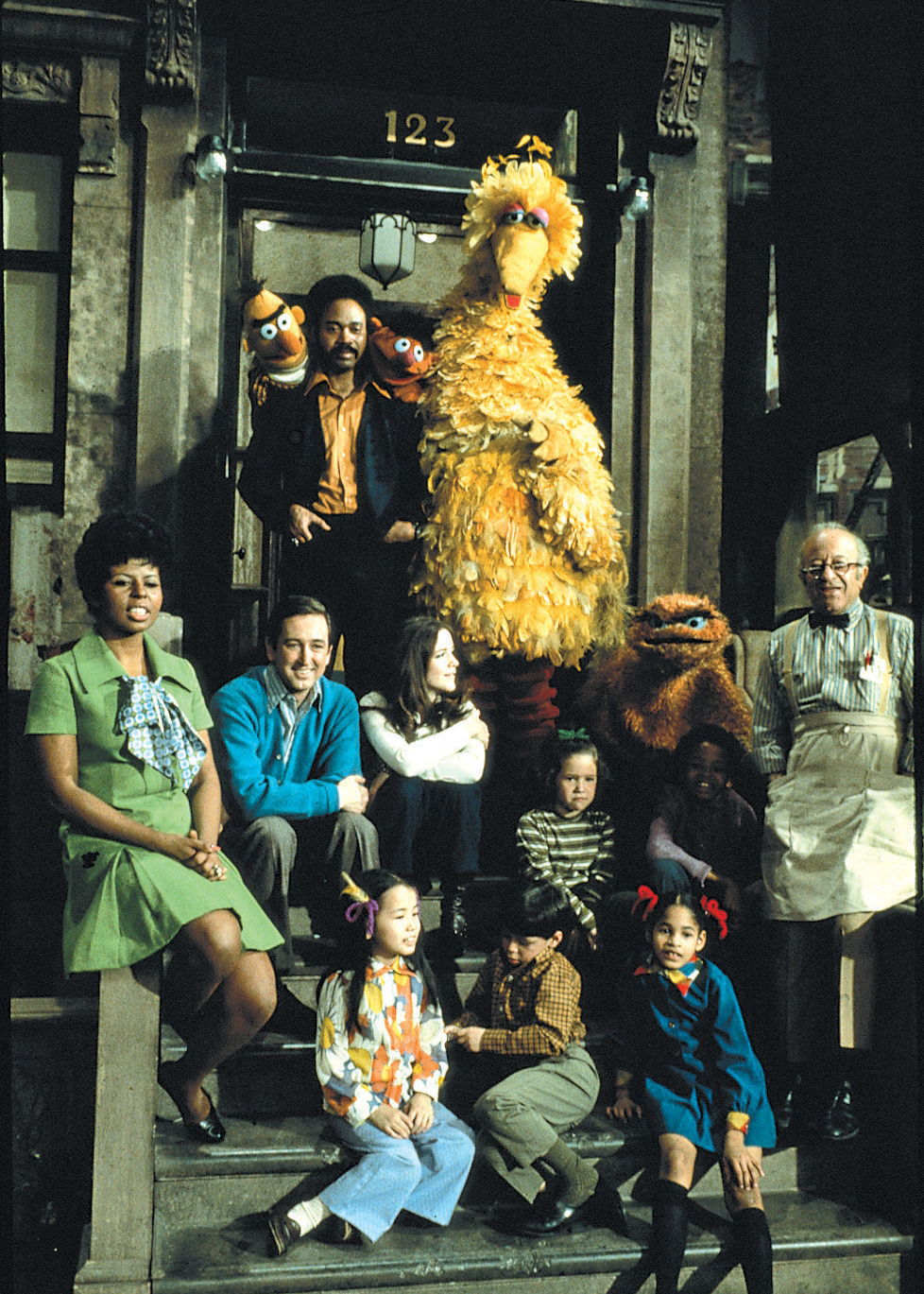 A photograph of the cast from Sesame Street Season 1 sitting on a stoop.