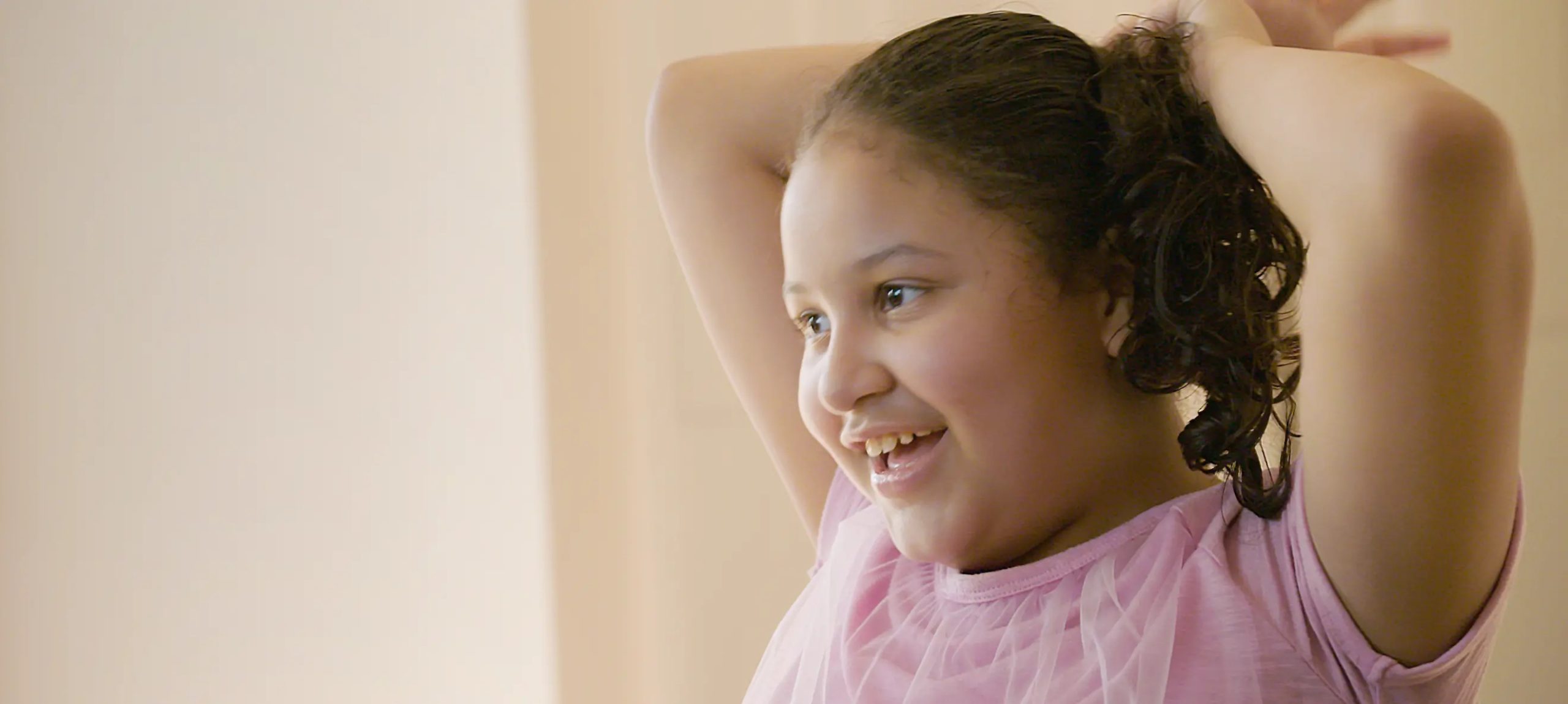 A young girl raises her arms over her head