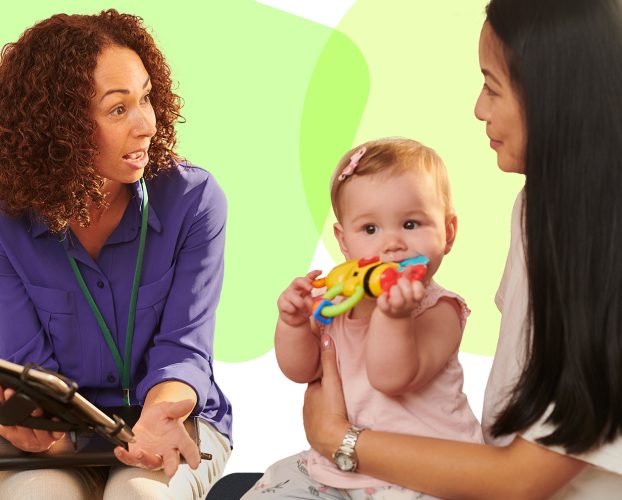 Two adults talk while a baby plays with a toy